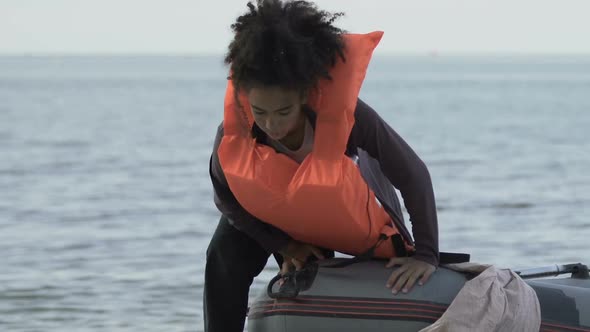Afro-American Girl in Boat Taking Off Life Jacket, Surviving After Shipwreck alt