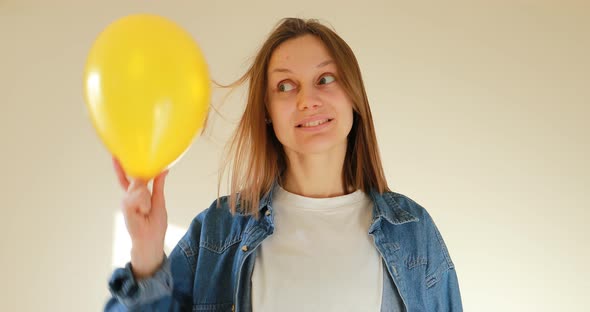 Portrait of young beautiful woman holding balloon in hand with attractive smile on white background.