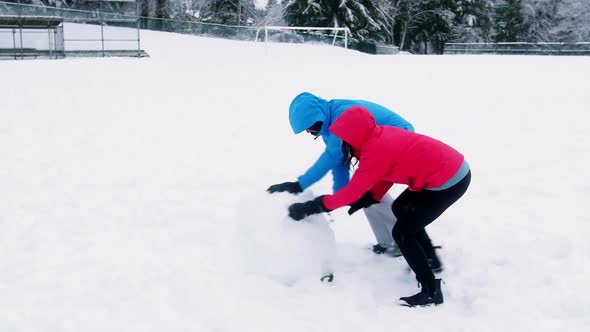 Couple pushing a huge snowball, Stock Footage | VideoHive