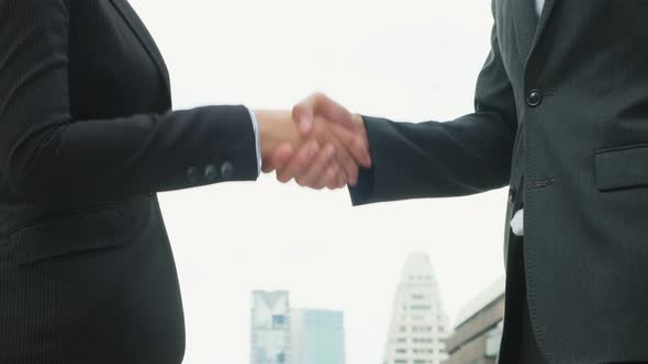 Close up of young business man and woman making handshake in the city.  Business deal and merger alt