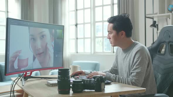 Asian Cameraman Using Desktop Computer For Editing Photos While Working At Home alt