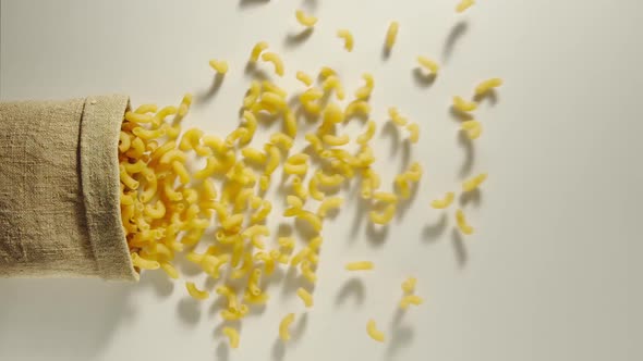 Bag Falls And Macaroni Are Poured Out Of It On White Background