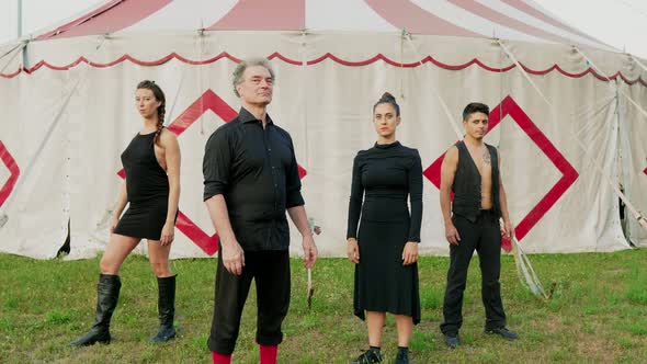Group of circus performers standing in front of tent alt