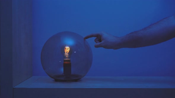 Unrecognizable crop person turning round lamp on and off with her finger alt