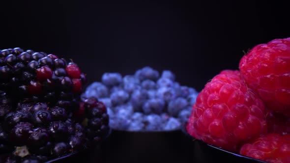 Blackberries, blueberries, raspberries in black bowls, on a black background. Probe lens view