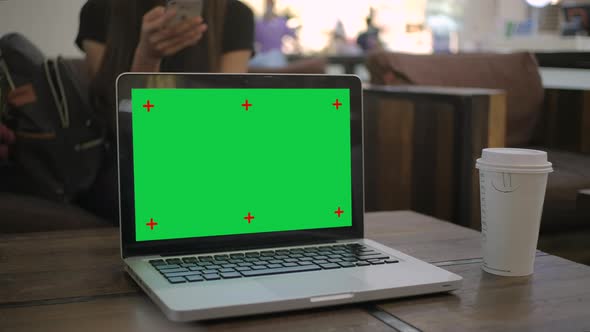 Chroma key green screen laptop computer set up for work on a cafe desk.