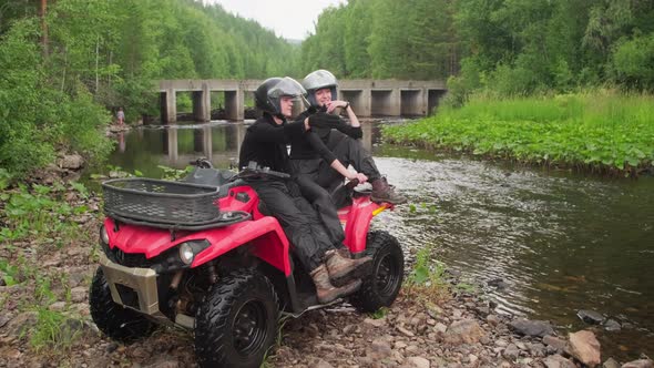 Cheerful Couple Sitting on Quad Bike and Enjoying Scenery in Forest alt