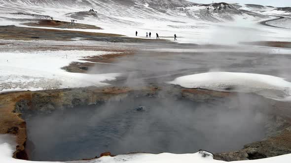 Close up of fumes rising up of snowy Geothermal Area in Iceland during winter - tilt up alt