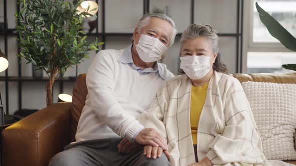 Elderly Asian couples wearing masks hug and encourage each other.