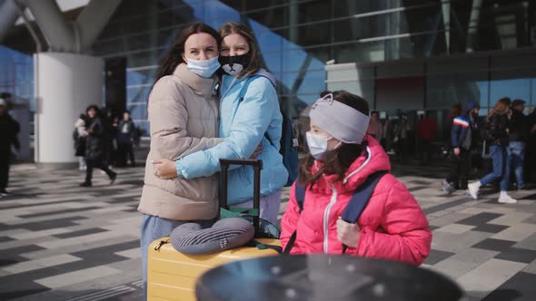 A Woman with Two Daughters Outside the Premises in Front of the Airport Terminal with Suitcases and