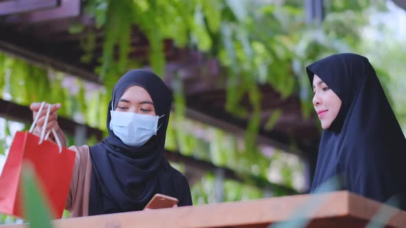 Muslim woman use mobile phone to pay with payment machine hold by shop staff alt