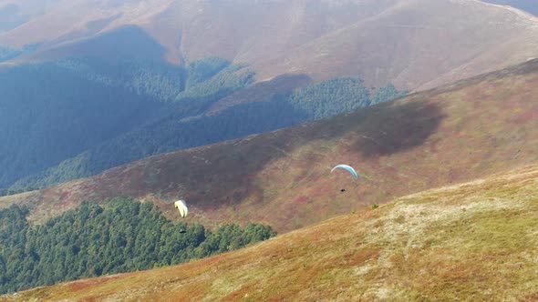 Two Paragliders Fly Over Mountain