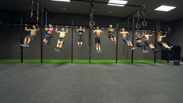 Group of athletes exercising chin-ups on rod at gym