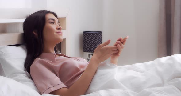 Woman is Laughing and Talking on Her Cell Phone While Lying in Bed