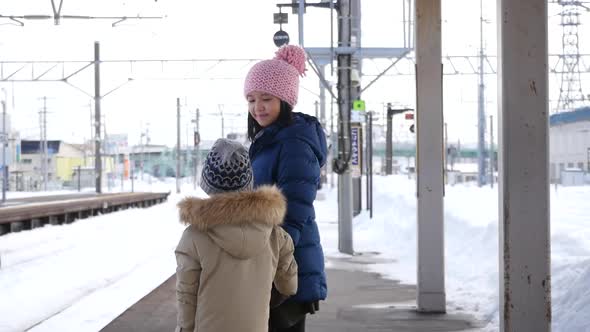 Asian Children Waiting Express Train On Railway Station Platform,Winter Travel Concept alt