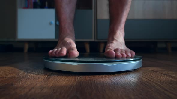 Person Male Measures the Body Weight Loss Standing on the Scale in the Living Room