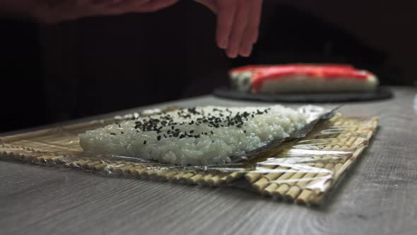 Chef's Hands Sprinkle Sesame Seeds on the Inside Out Sushi. Japanese Chef in alt