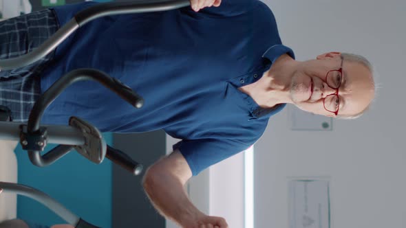 Vertical Video Portrait of Elder Man Healing Physical Injury with Stationary Bicycle alt