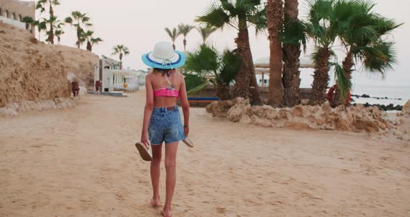 Teen Girl is Leaving the Beach in Tropics Carrying Slates in Her Hands