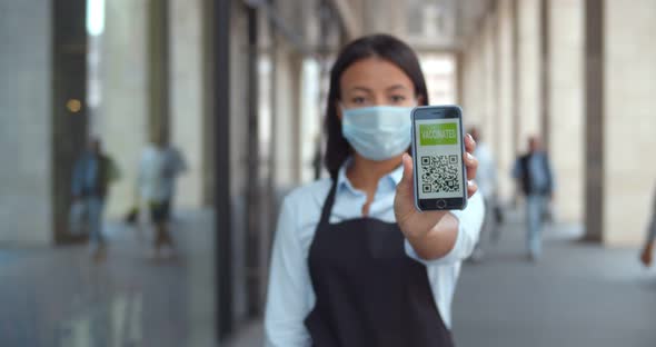 Afro Female Restaurant Owner in Safety Mask Showing Cellphone with Vaccinated Qrcode at Camera alt