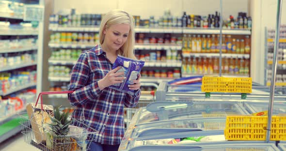 Woman Opening Glass Door of the Fridge and Taking Frozen Food at Supermarket alt