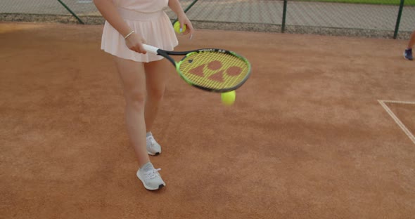 Professional Sportswoman Serving Tennis Ball to Opponent on Clay Court Outdoors Summer Background