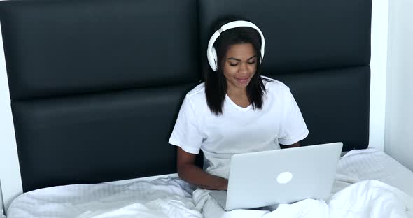 Black Woman listening music in headphones at home.