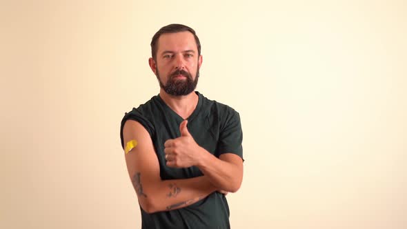 Man with Plaster on Shoulder After Vaccination Holding Thumb Up Gesture