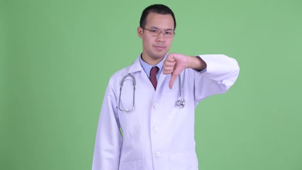 Sad Asian Man Doctor with Eyeglasses Giving Thumbs Down alt
