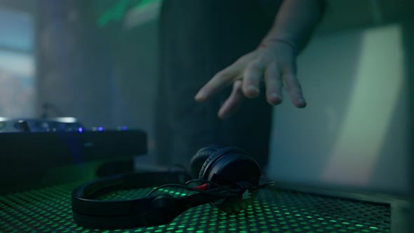 Deejay Coming Up to Desk Taking Headphones Putting It to Ear and Listening to Music alt