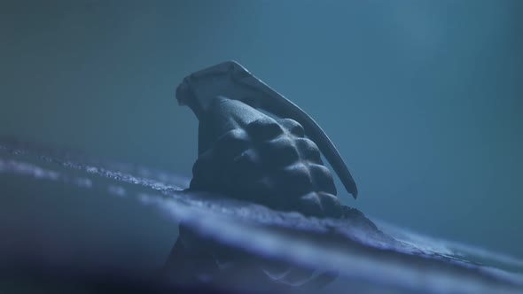 Close up of a hand grenade lying in the mud. Bright explosion at the end. 4K HD alt