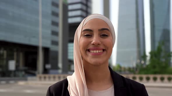 Young arabian business woman smiling on camera with city in the background