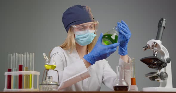 A Lab Worker Is Reviewing the Reaction of Elements in the Flask. Experiments in the Laboratory.  alt