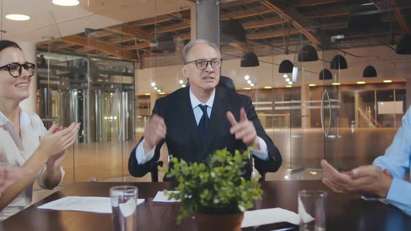 Diverse Business Team Clapping Hands and Smiling During Boardroom Meeting alt