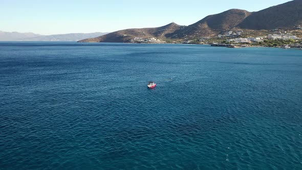 Aerial View of a Speeding Motor Boat in a Deep Blue Colored Sea. Spinalonga Island, Crete, Greece