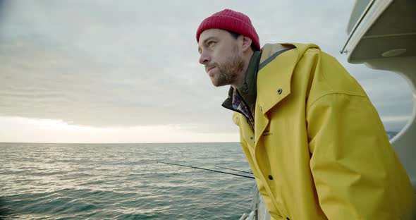 Fisherman Looks at the Horizon and Into the Water Smiles on the Boat at Sunrise