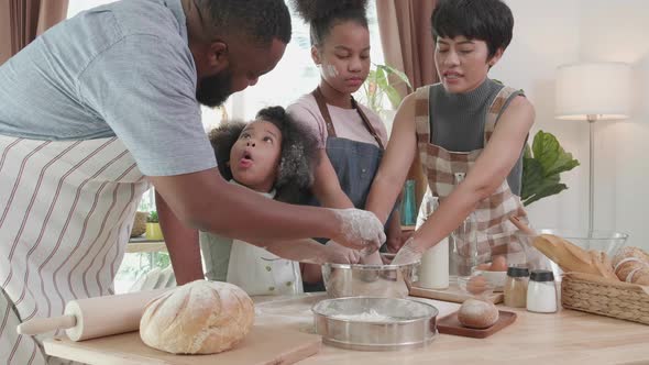 African American family with little adorable daughters wear aprons cooking together