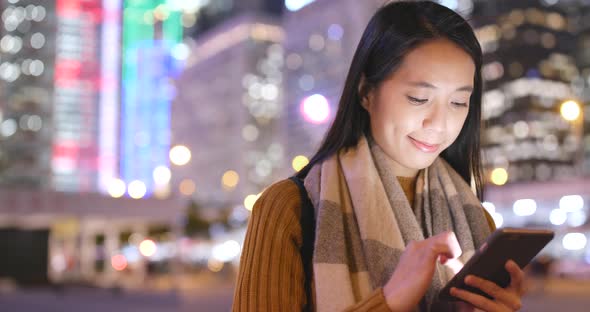 Woman working on cellphone in the city at night alt