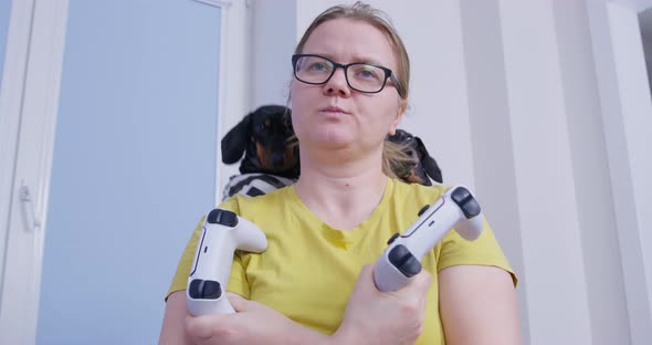 Young Woman with Dissatisfied Look Holds Two Controllers for Video Game Console Arms Crossed Over