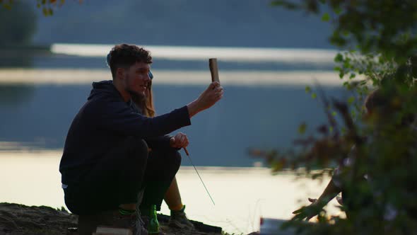 Travellers sitting by a lake and talking alt