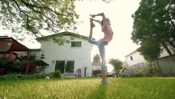 The Child Is Engaged in Acrobatics at Sunset in Back Yard. Slow Motion. Move Camera alt