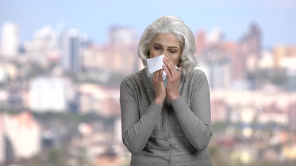 Sneezing Caucasian Woman on Blurred Background alt