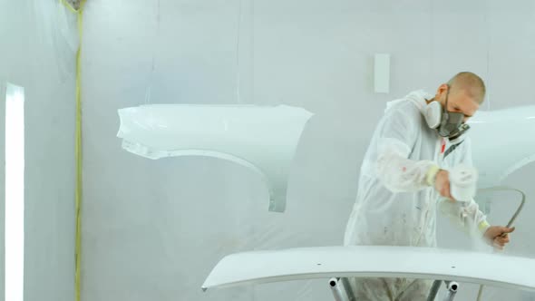 Mechanic painting car parts with electric spray gun 4k alt