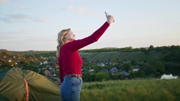 a Young Woman is Happy to Communicate in Video Communication Through a Phone on the Mountain Hills alt