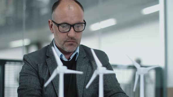 Business people examining wind turbine models in office