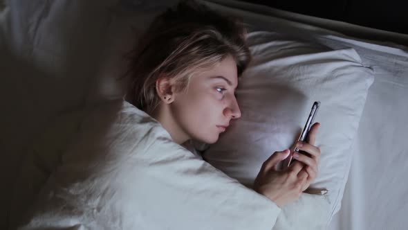 Tired Woman Browsing Smartphone in Bed