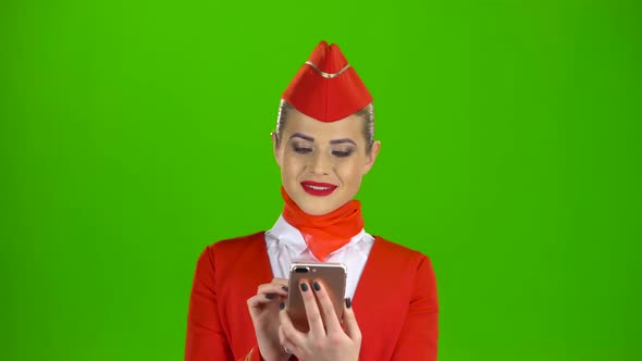 Girl in Red Attire Looking at the Phone Is Flipping Through the Pictures. Green Screen alt