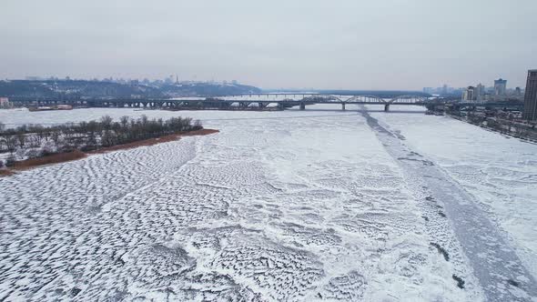 Flight Over the Frozen Dnieper River Near the Bridge Overlooking the European City of Kyiv
