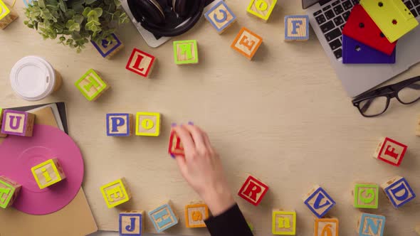 Woman Hand Arranging Wooden Cubes with Word PODCAST Top View alt