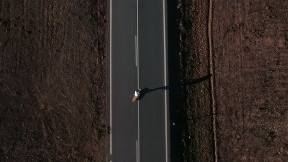 Aerial Drone Shot of Man Ride Longboard on Road
